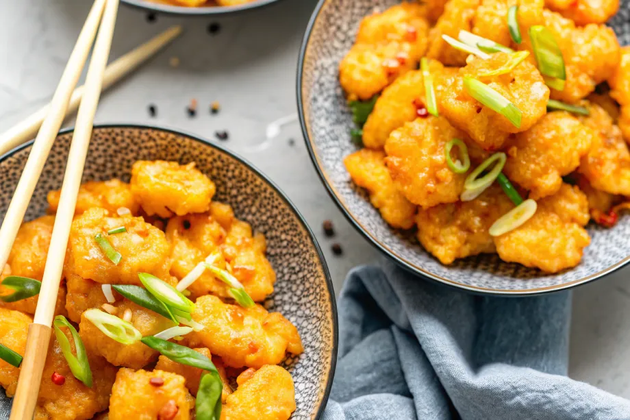 Two bowls of Boom Boom Shrimp coated in creamy orange sauce,