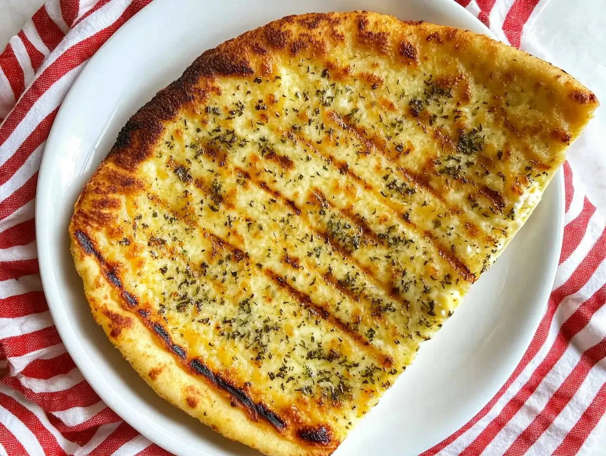 A slice of golden, crispy cottage cheese flatbread topped with herbs, served on a white plate.
