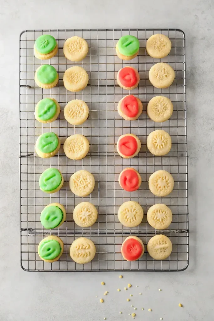 Wafer cookies with green and red cream filling, arranged on a cooling rack.