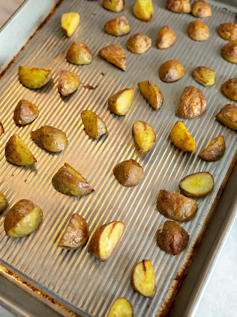roasted baby potatoes arranged on a baking sheet, showing their golden-brown color and crispy edges.