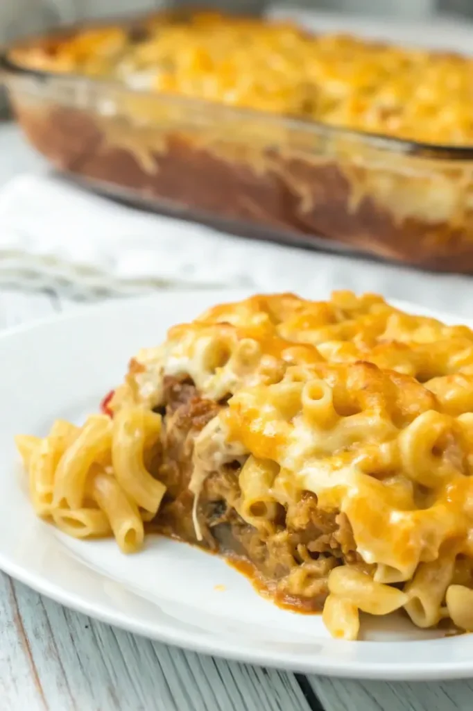 A plated serving of Mac and Cheese Meatloaf Casserole with melted cheese on top and ground meat visible inside.