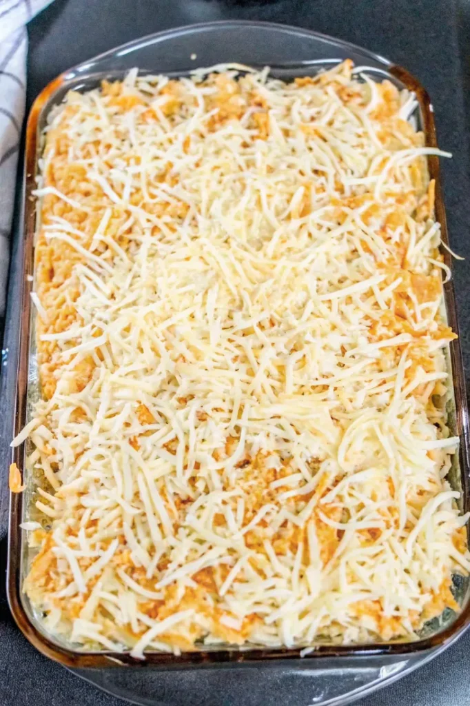 A casserole dish topped with a layer of shredded mozzarella and cheddar cheese, ready to be baked.