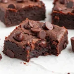 Fudgy sweet potato brownies with melted chocolate chips, one with a bite taken out.