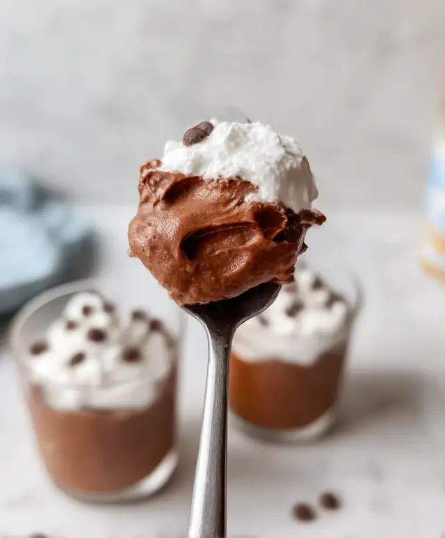 close-up of spoonful of chocolate avocado pudding with whipped topping